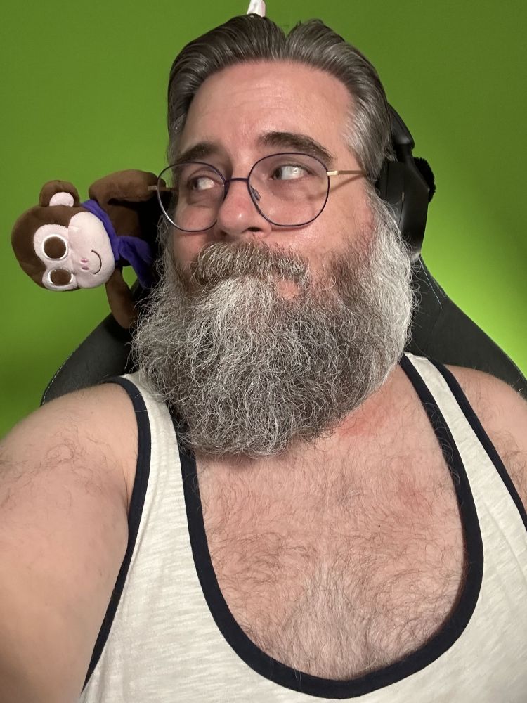 Me wearing a cream tank top, looking over at brown plush Chair Monkey, flopping sideways from the back of the chair above my shoulder