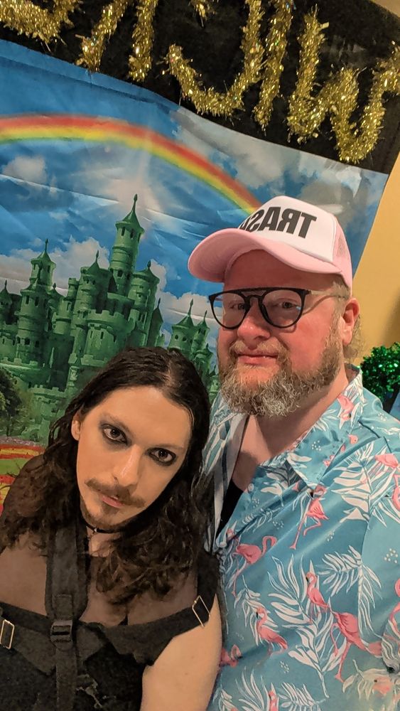 goth enby with hawaiian shirt bear bf in a pink trash hat