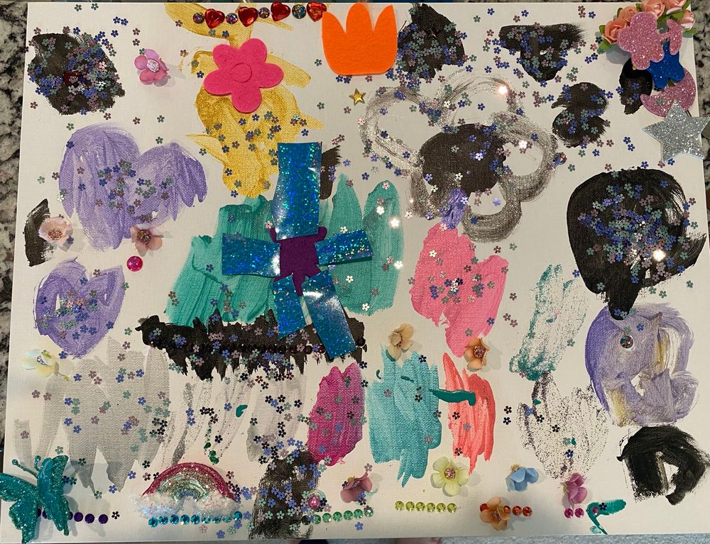 A child’s art project. A smattering of paint smears, rhinestones, sparkles, and other fun shapes glued all over it. 