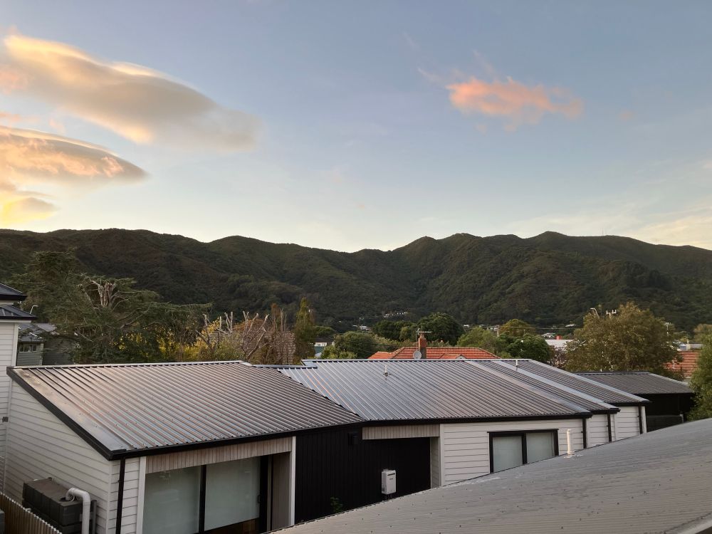 Roof tops of sm  as lol sinhh go Le levels in the foreground. Eastern Hills in the background and bits of fluffy orange clouds in the sky. 