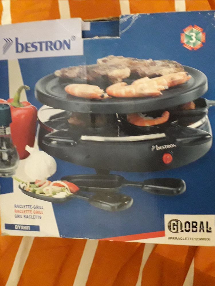 Carton d'un appareil à raclette suisse, où des crevettes se font "griller la face"