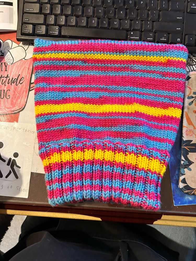 A knitted hat in pink, blue, and yellow yarn