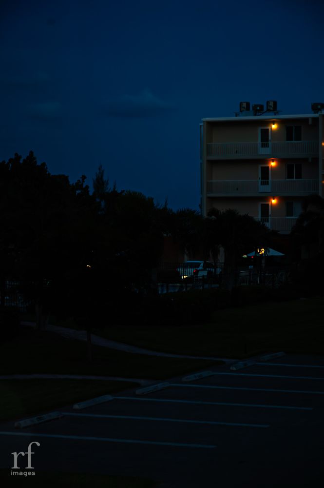 The darkness almost swallows the yellow/orange lights on a condo building. 8:54 pm