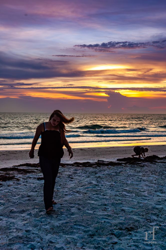 A young woman heads off the beach during sunset. 