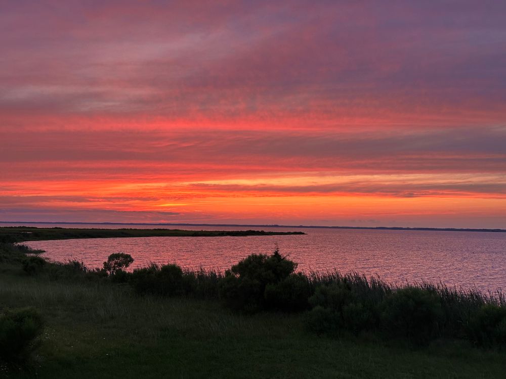 View of a cloudy sunset over a river featuring pink, purple, and orange 