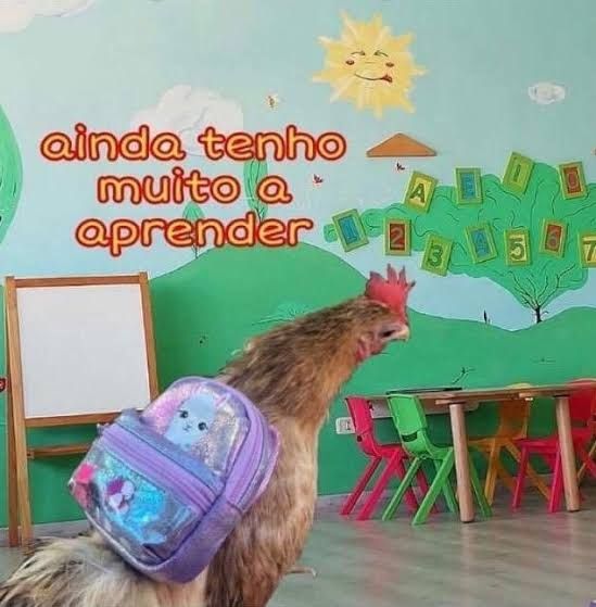 Meme da galinha ainda tenho muito a aprender. A foto de uma galinha com uma mochilinha roxa nas costas. Ela está numa sala de aula bem colorida, provavelmente infantil, com desenhos de montanhas, nuvens e um sol na parede. Acima da galinha está escrito: ainda tenho muito a aprender.