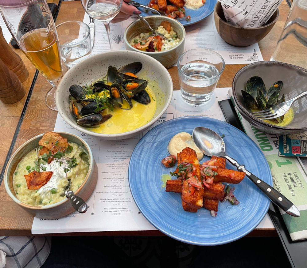 Three plates of food: herb-pea risotto, butter drenched mussels and fried halloumi. 