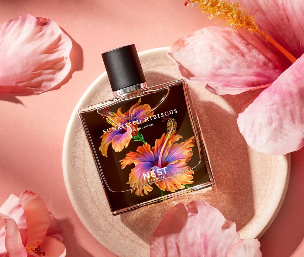 Promo shot for hibiscus kiss by nest. The bottle is rectangle with a black lid with orange and purple hibiscus flowers on the cover for the bottle 