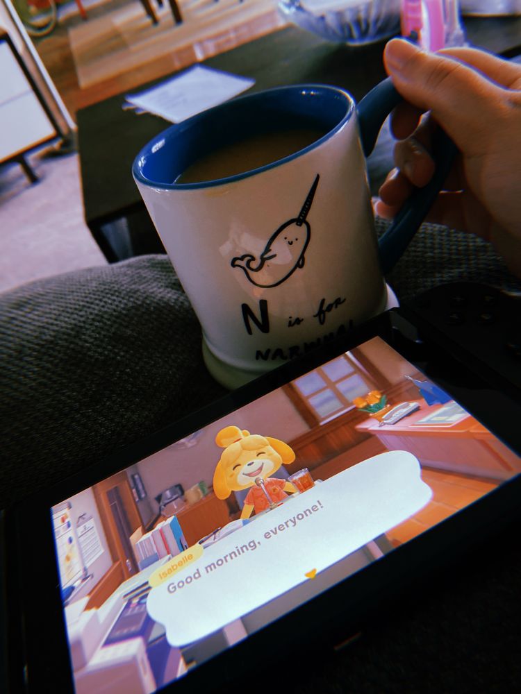 My n is for narwal mug it’s white with blue accents, it’s being posed next to Isabelle’s good morning announcement in animal crossing on the switch 