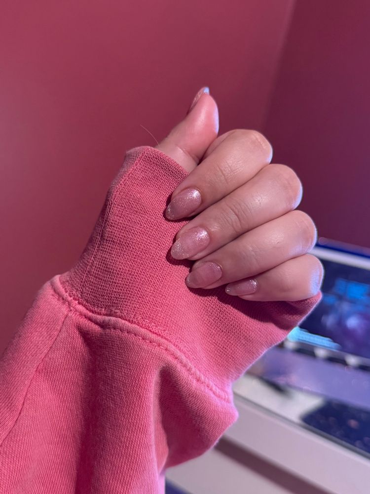 A photo of my hand showing my pink ‘cat eye’ nails against a darker pink sweater 