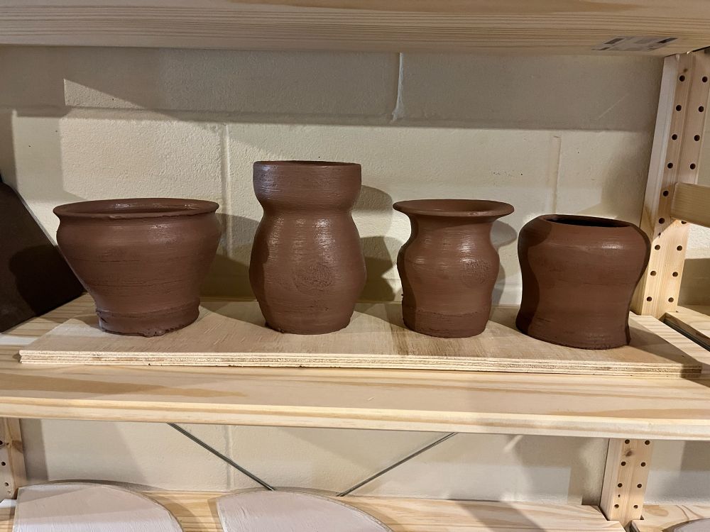 A series of four wheel thrown vases and bowls made out of a dark brown terrracotta clay.