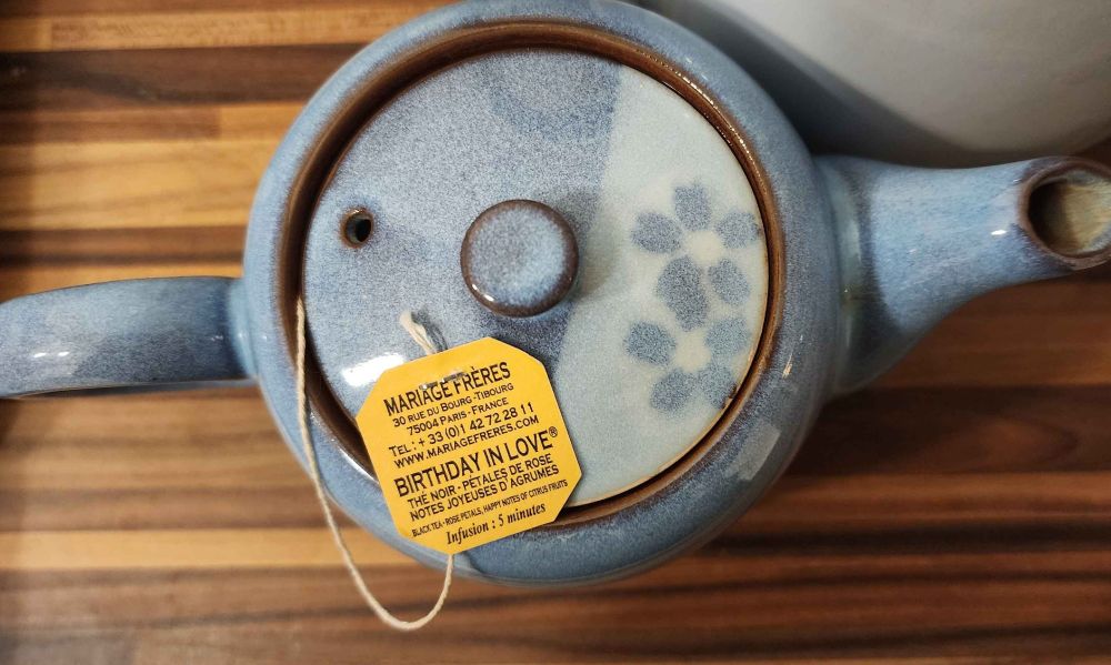 Un sachet de thé noir sur une théière bleue