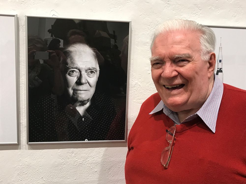 Mike Dinn poses in front of a black and white portrait photo of himself.