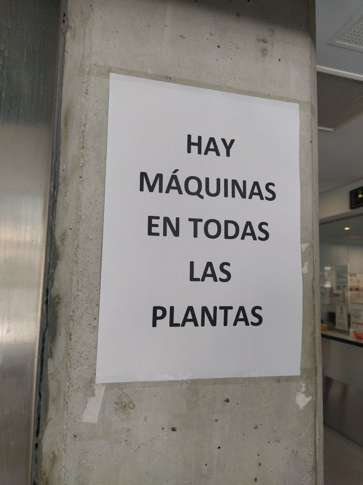 Impreso en un folio en letras muy grandes está el aviso "

HAY MAQUINAS EN TODAS LAS PLANTAS 

" 

pegado en una columna de hormigón 