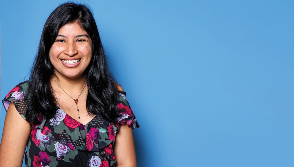 Portrait of a woman against a blue photo backdrop.