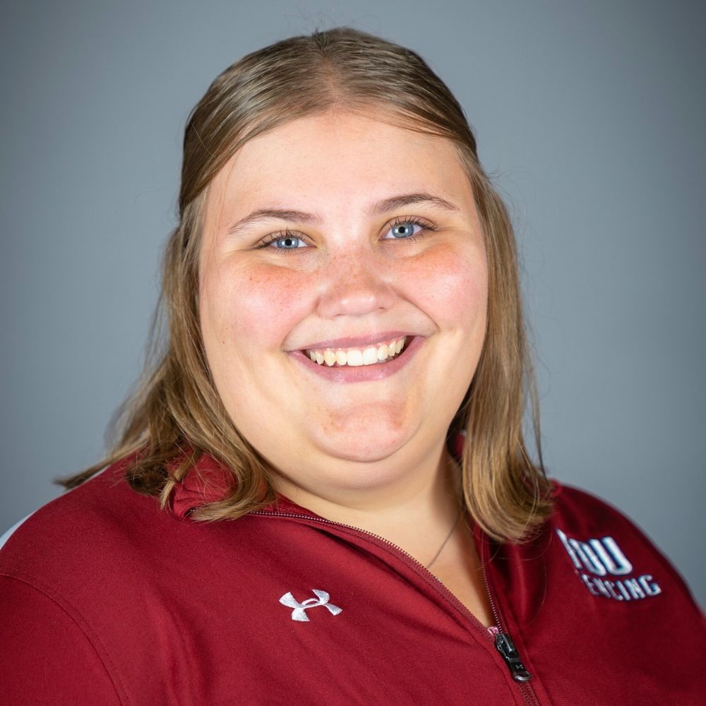 a headshot of a student. she wears a burgundy polo with the FDU Knights Fencing logo and the Under Armour logo on it.