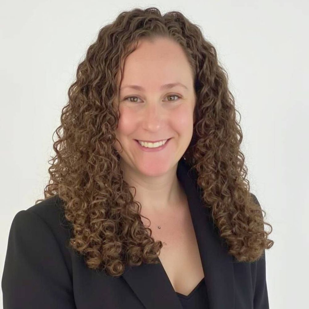 portrait of a woman against a wall. she wears a black blazer.