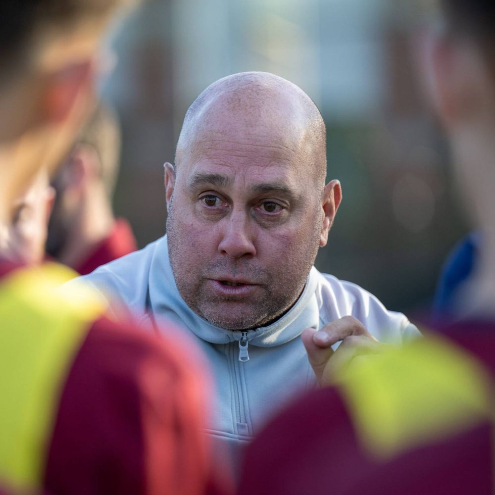 A man speaks to his team standing in a circle.