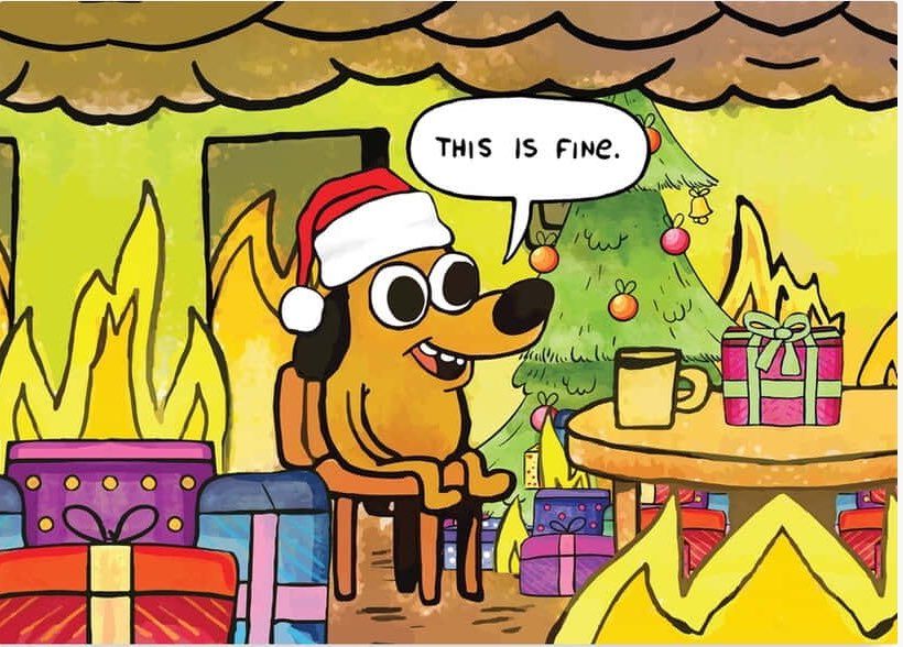 Cartoon dog from the "this is fine" meme sitting in its living room with a Christmas tree in the background, a red Santa hat on and and presents around.
