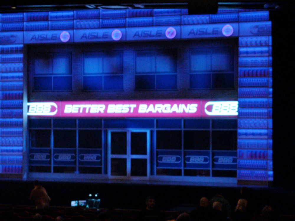 A stage set showing the entrance to Better Best Bargins for Here & Now - The Steps Musical 