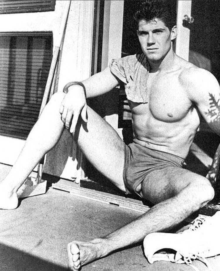 Shirtless guy in short shorts sunning himself in a doorway. Jewels visible the crotch.