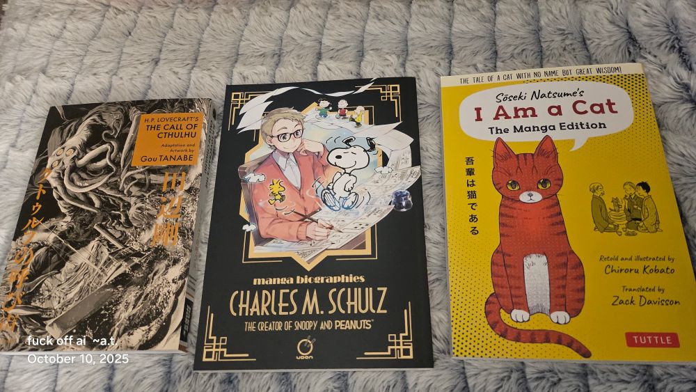Photo of three paperback books, left to right: The Call of Cthulhu artwork by Gou Tanabe with an illustrated monser on the cover. Manga Biographies Charles M Schulz with an illustration of a young man with glasses drawing up a Snoopy illustration that is dancing on pages of a comic illustrations. On the right a yellow book with an orange cat drawn on it and in a dialogue bubble overhead is the title: Soseki Natsume's I AM A CAT THE MANGA EDITION Retold and illustrated by Chiroru Kobato Translated by Zack DAvisson publisher Tuttle 
