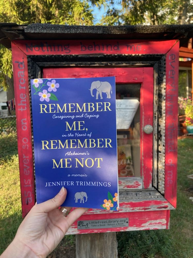 One of my amazing critique partners placing my new book, Remember Me, Remember Me Not (purple book, with yellow font, flowers and elephants on the cover) in a Little Free Library, in Detroit.