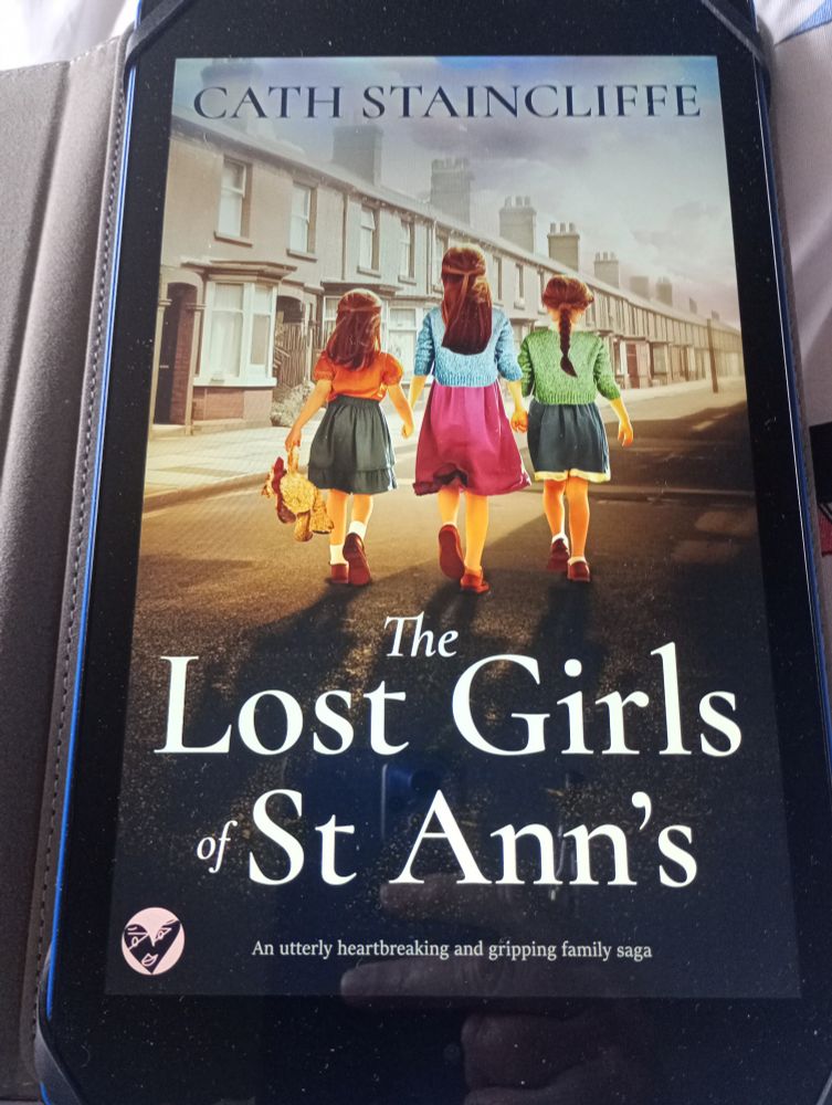 Book cover showing three young girls walking down a typical Manchester street of terraced houses in earlier times. The Lost Girls of St Ann's by Cath Staincliffe
