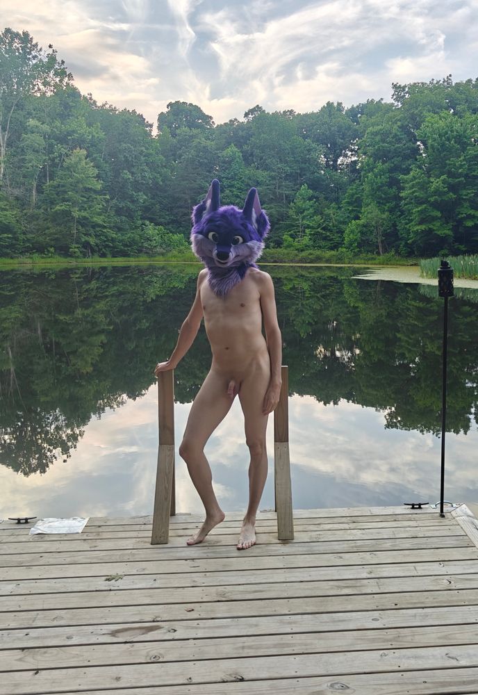 Niqnaq standing on a dock surrounded by a lake, nude