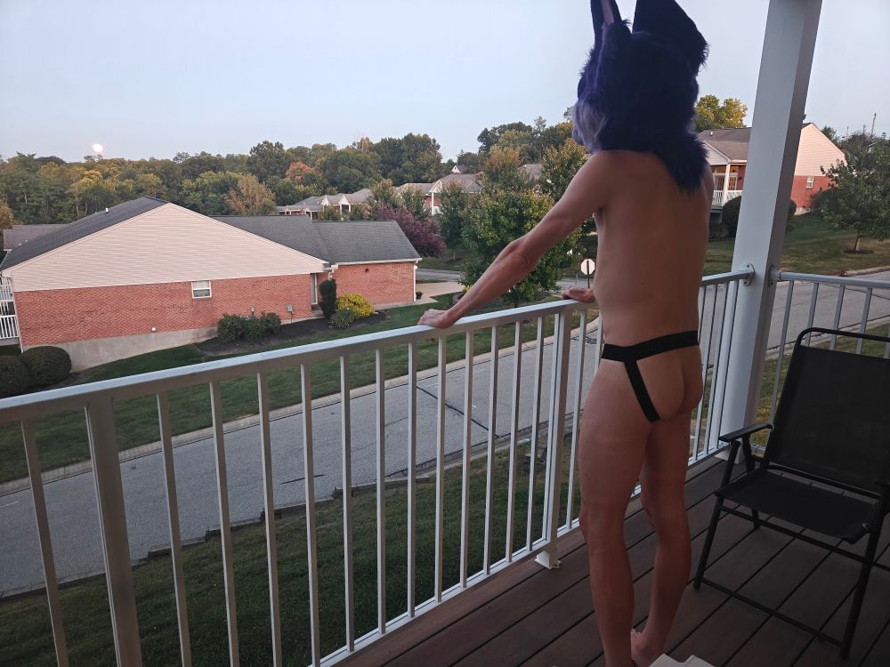 Looking out at scene from balcony, in jockstrap 