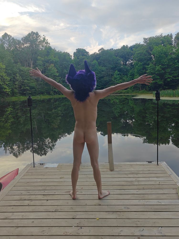 Niqnaq standing on a dock surrounded by a lake, nakey