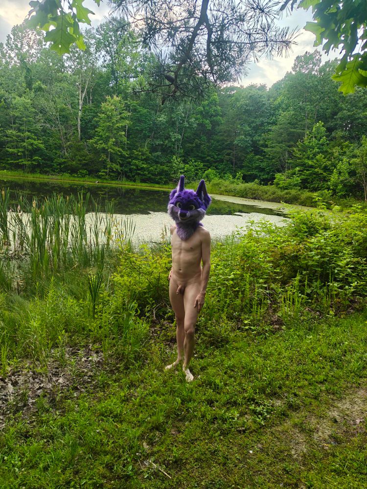 Surrounded by green grass, trees, and a lake, nude 