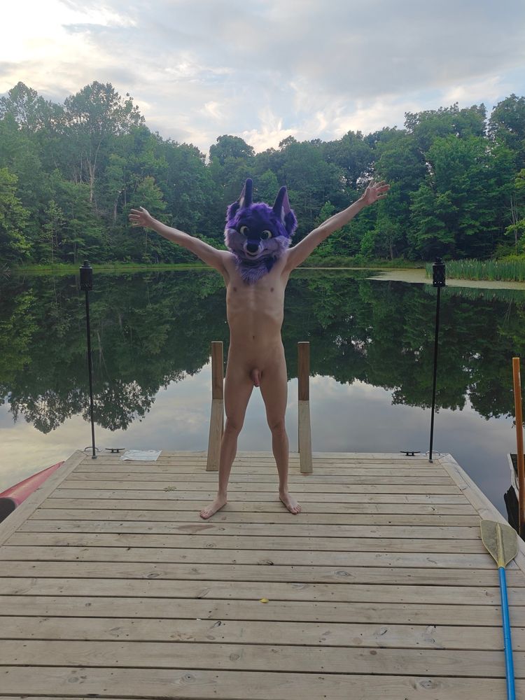 Niqnaq standing on a dock surrounded by a lake, nakey