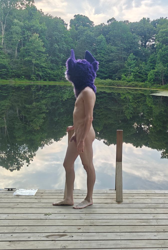 Looking out at the water and surrounding landscape, nude
