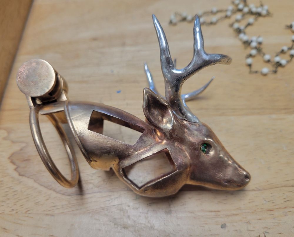 bronze chastity cage with a deer head on the head. deer has sterling silver antlers and cubic zirconia eyes.