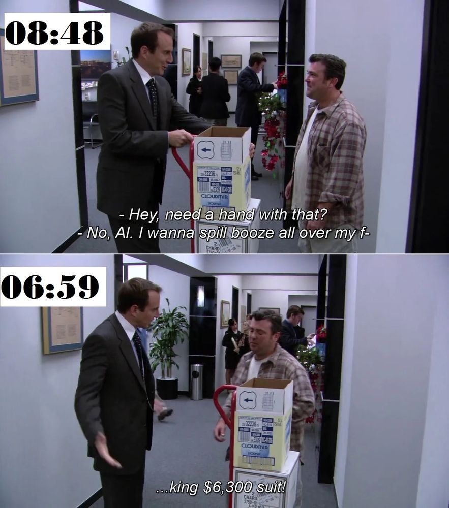 Gob, dressed sharply in a dark suit and tie, stands beside a box-laden dolly in an office hallway decorated for the holidays. He offers to help a casually dressed man in a plaid flannel shirt. The man sarcastically declines, clearly annoyed, and soon after accidentally spills something on Gob’s suit. Gob explodes in frustration, arms outstretched, furiously emphasizing the cost of his “$6,300 suit” as the man looks sheepishly back.