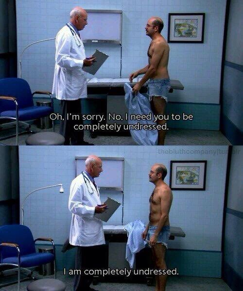 In a sterile, fluorescent-lit exam room, Tobias stands facing a doctor. Tobias wears nothing but extremely tight cut-off denim shorts, holding a crumpled shirt in one hand. The doctor, dressed in a white lab coat and holding a clipboard, politely tells Tobias he needs to be “completely undressed.” In the next frame, Tobias responds with wide-eyed sincerity, insisting, “I am completely undressed,” still wearing only the tiny shorts. His obliviousness is matched by the doctor’s awkward silence.