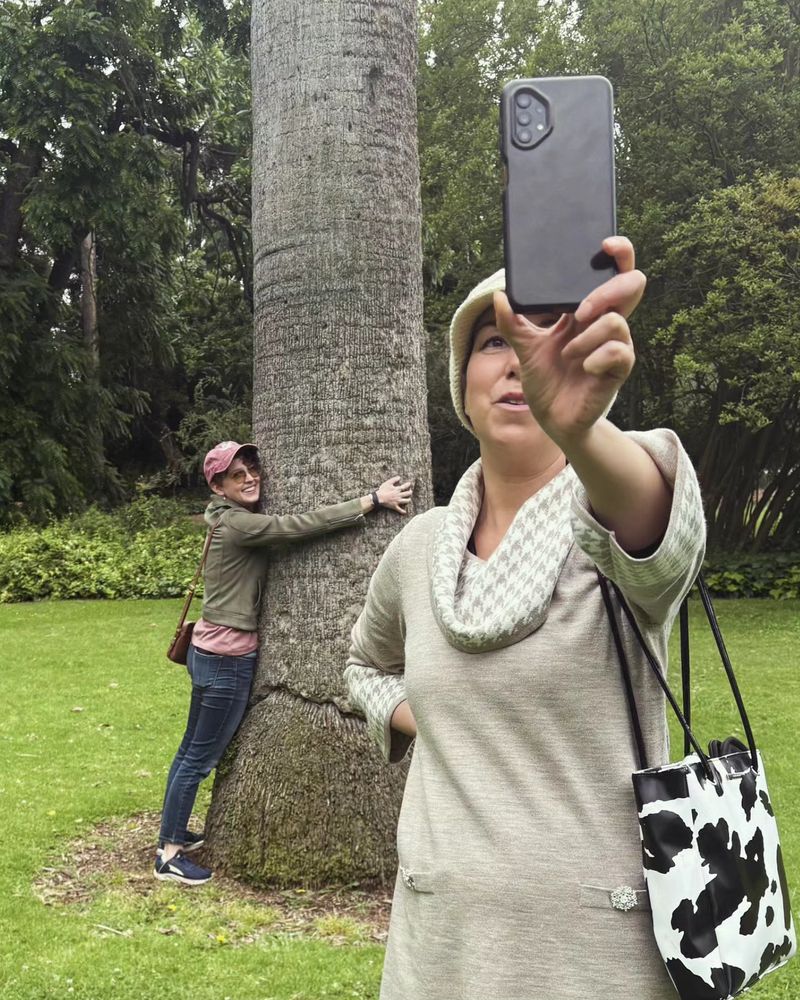 Chloe hugging the tree that young Stede ran into while Carly livestreams on her phone