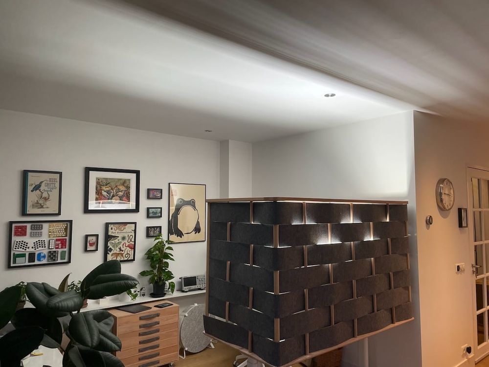 a wood and felt desk partition containing an extremely bright uplight, illuminating the white ceiling and surrounding walls