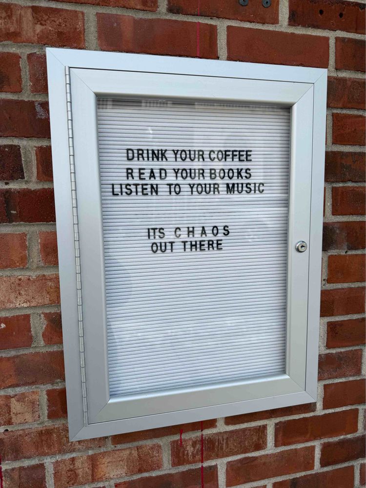 A sign that says: Drink your coffee. Read your books. Listen to your music. It’s chaos out there.