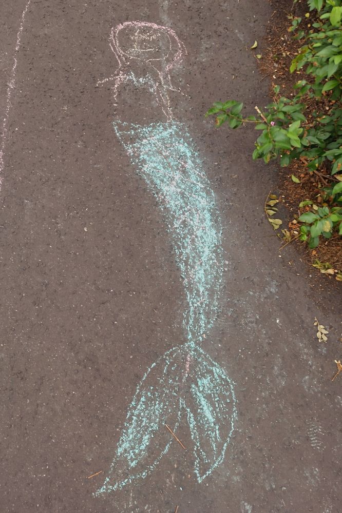 Photo of a mermaid drawn in chalk on a pavement by some kids.