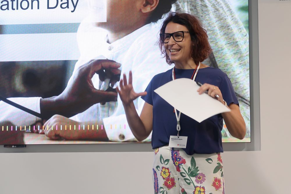 Manuela D'Agata, Head of Sales Development and Marketing at Tecan, stands in front of the presentation screen to introduce the day. 