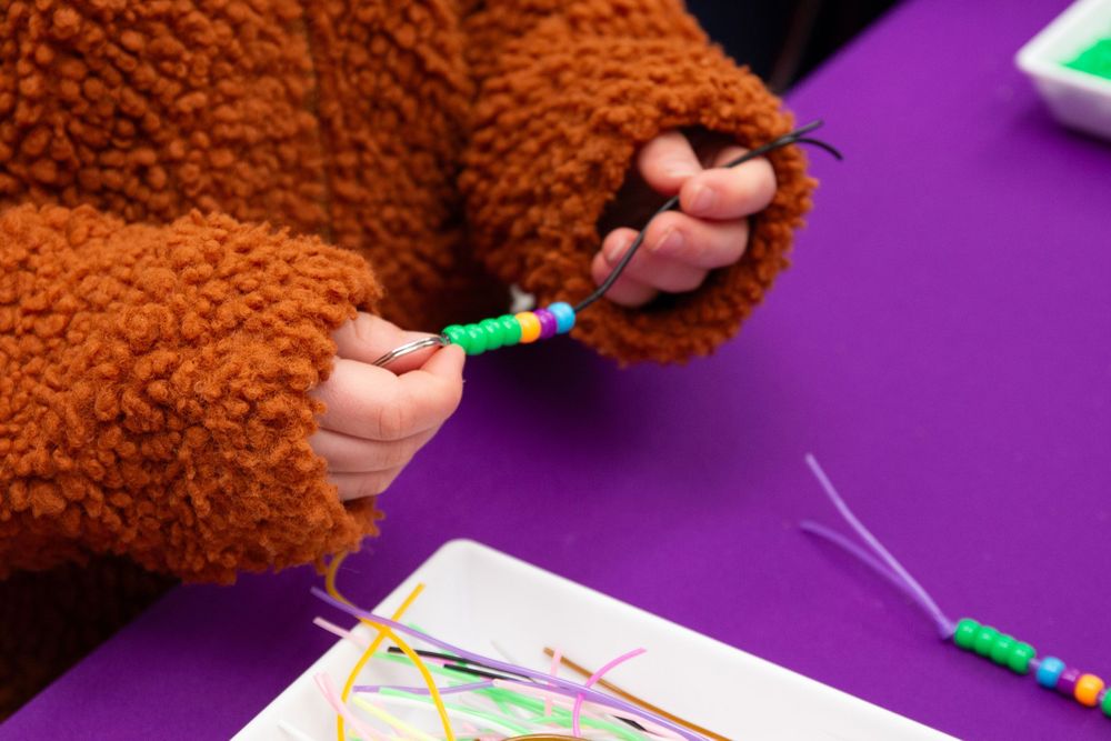 Child's hand holding colourful beads on a string.