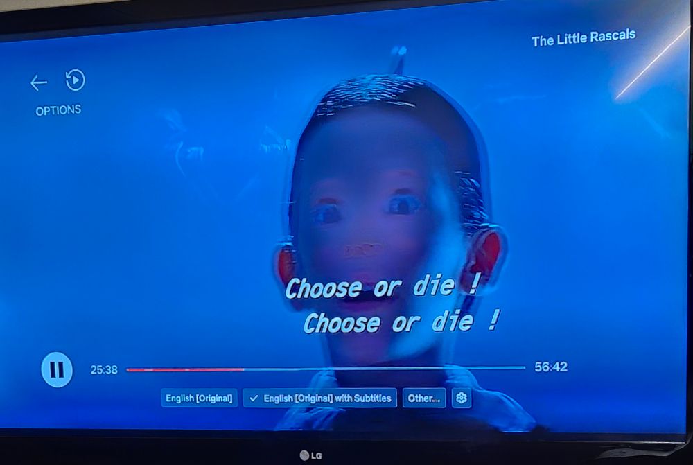 A still image of the movie Little Rascals. Theres a caption "choose or die !" twice, as the image is the boy Alfalfa between two frames, thus the image is distorted where he is dark blue and no eye brows with motion blur.