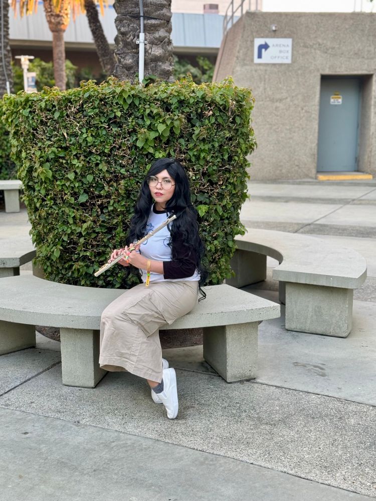 Jade Harley from Homestuck cosplayer in front of a hedge sitting on a cement bench.