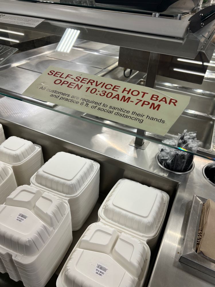 Photo of empty hot bar at grocery store with sign stating food available from 10:30am-7pm. Photo was taken at 6:37pm.