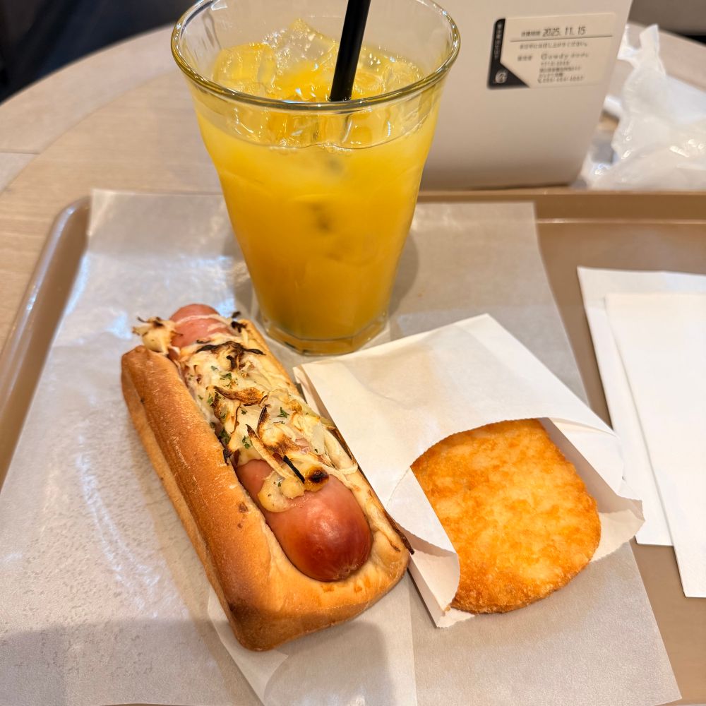リトルマーメイドのイートイン。デンマークソーセージドッグ、ハッシュドポテト、オレンジジュースがトレイに敷いた紙の上に並んでいる。