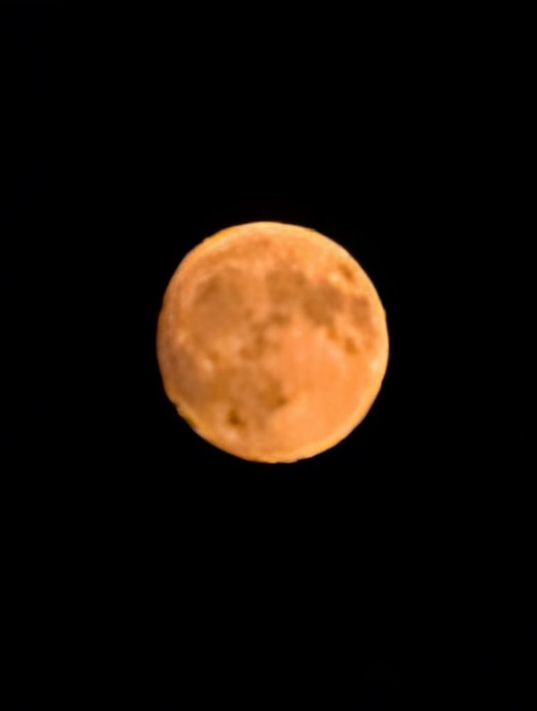 Orange-red nearly full moon against a dark sky