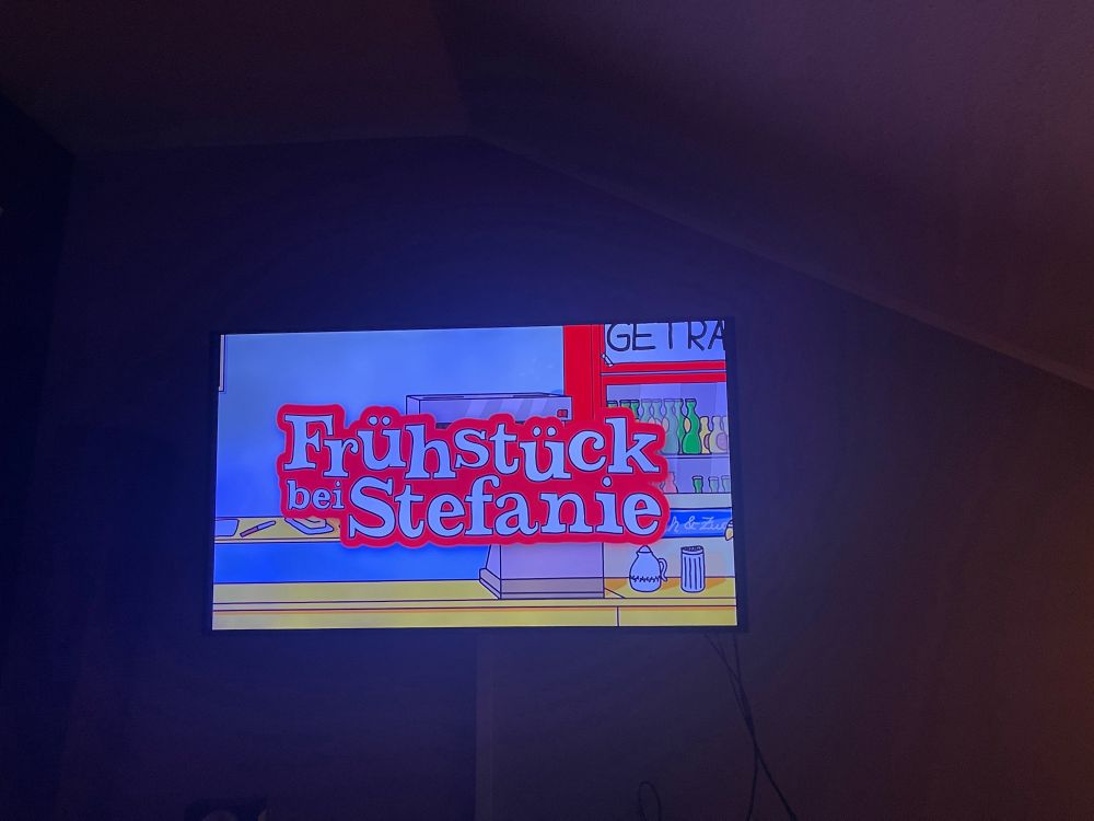 Fernseher, auf dem das Logo von "Frühstück bei Stefanie" abgebildet ist.
