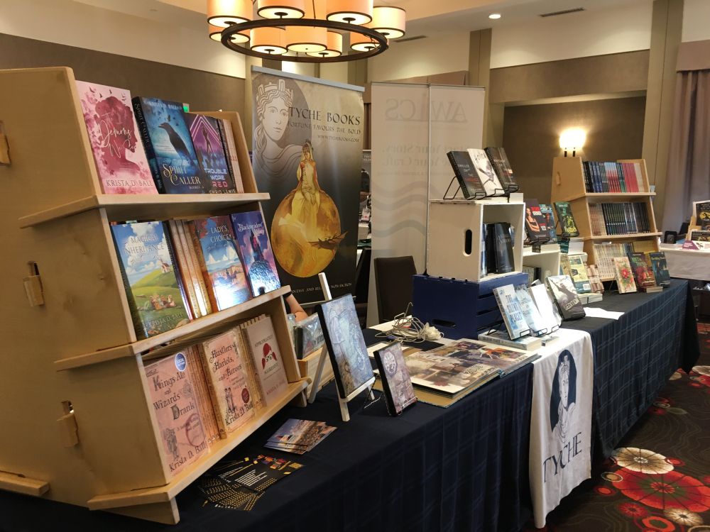 Tyche tables at When Words Collide, with books on shelves & stacked on the table.